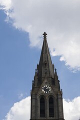 The tower of the church of St. Ludmila, in the background a blue sky with white clouds. Peace Square, Prague, Czech Republic.