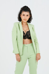 Portrait isolated studio full body shot of Asian young sexy curly hairstyle fashion model in green formal suit with black lace lingerie bra and high heels standing posing alone on white background