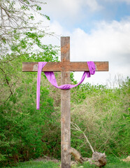 Wooden cross with a purple ribbon on a cloudy day