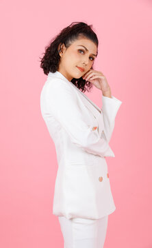 Portrait studio shot of Asian sexy curly hairstyle professional successful businesswoman in white fashionable casual suit with lace lingerie crop top bra standing look at camera on pink background