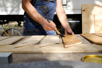 white caucasian man painting wood for the interior of his motor home. Mobile home repair.