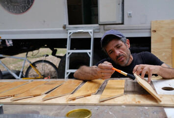 white caucasian man painting wood for the interior of his motor home. Mobile home repair.