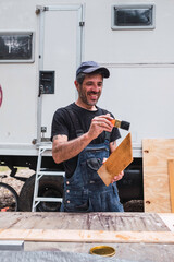 white caucasian man painting wood for the interior of his motor home. Mobile home repair.