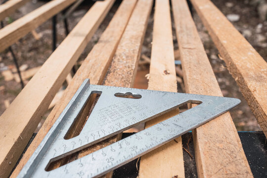 stainless steel triangular ruler on wooden slats.