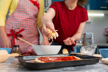 Two young women cooking a pizza. Hands close-up. Homemade cooking concept