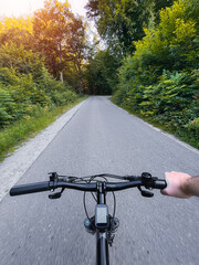Close up of bicycle handle bar. First-person view of bicycle riding. Man riding a bike. Holding bike handlebar with one hand. Summertime outdoor leisure sport activity.