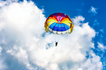 Paragliding using a parachute on background of blue cloudy sky.