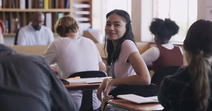 Learning, education and teen student in a high school classroom with students in a exam. Portrait of a happy girl with a smile in class looking back from learning, studying and working at a desk