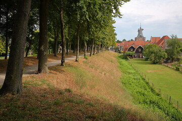 Fototapeta na wymiar The footpath around the fortified city of Elburg, Gelderland, Netherlands, with the well preserved old city gate Vischpoort in the background