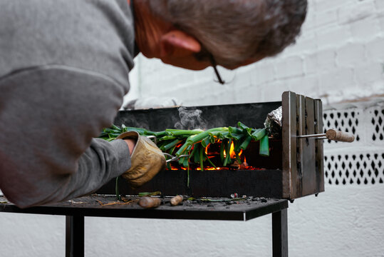 Man grilling calcots on terrace