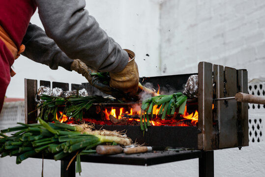 Unrecognizable person grilling calcots on terrace