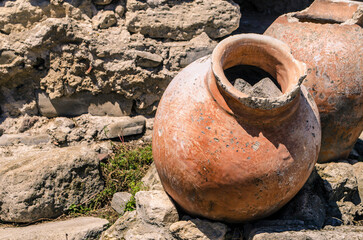 An ancient antique clay jar lies among the ruins of a Mediterranean city. T