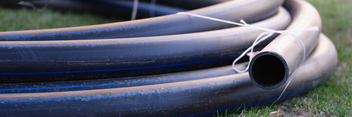 Twisted pipe for irrigation system lying on green lawn closeup
