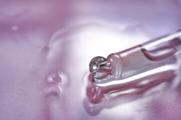 Dropper with serum or cosmetic oil on a pink background.