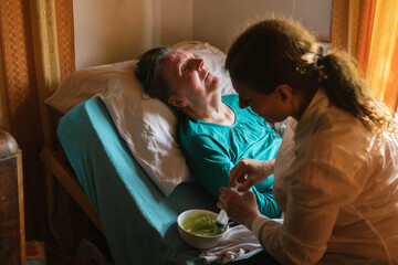 Social worker feeding disabled mature female