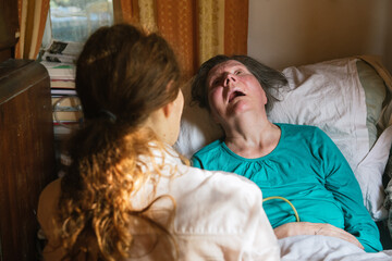 Social worker feeding disabled mature female