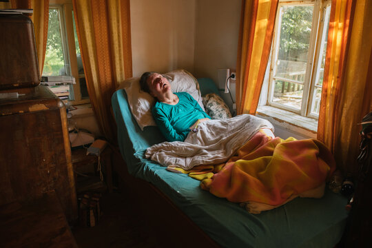Paralyzed elderly lady lying on bed at home