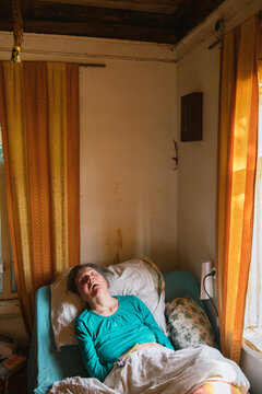 Paralyzed elderly lady lying on bed at home