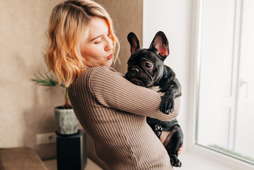 Woman holding a french bulldog puppy on her hands cute lovely moment of dog lover owner. Happy pet living in the apartment