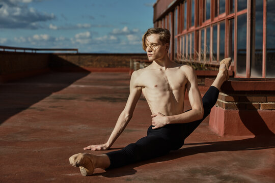 Young slender performer doing splits on roof