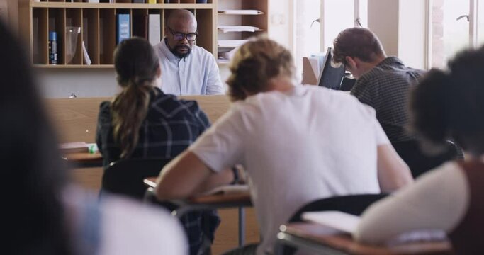 Education, learning and student writing an exam or test in a class at school with a teacher. Classroom, students and high school with people studying for growth and development at a desk or table