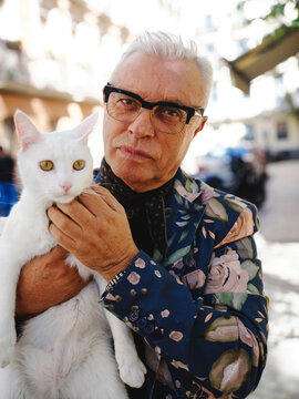 Stylish man with white cat in city
