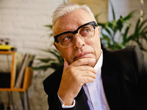 Stylish senior man sitting in cafe and looking away