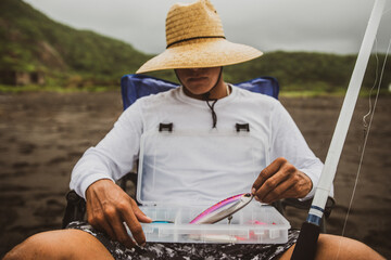 Unrecognizable fisherman with kit of fishing tackle