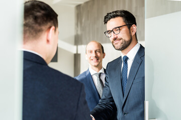 Group of confident business people greeting with a handshake at business meeting in modern office or closing the deal agreement by shaking hands.