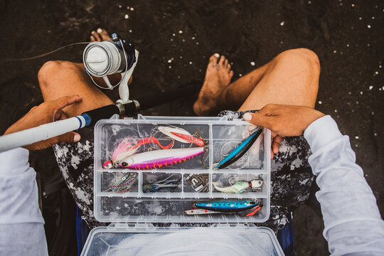 Unrecognizable fisherman with kit of fishing tackle