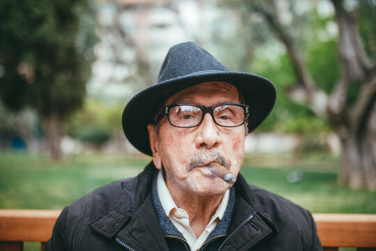 Elderly man smoking cigar on street