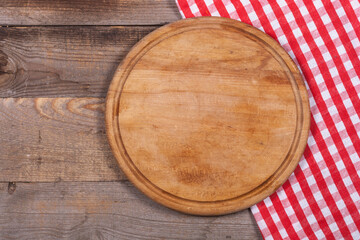 Round kitchen stand for cutting products and a red and white towel on a wooden background close-up