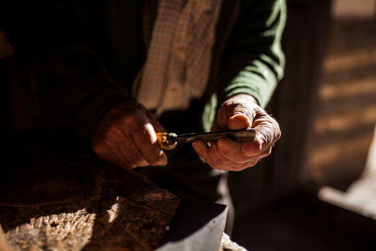 Crop elderly carpenter with chisel