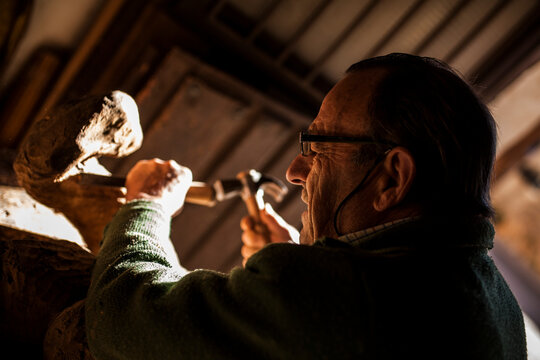 Elderly carpenter working with wood