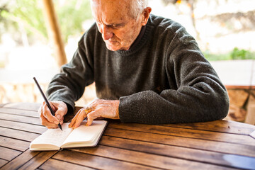 elderly man writing in his notebook