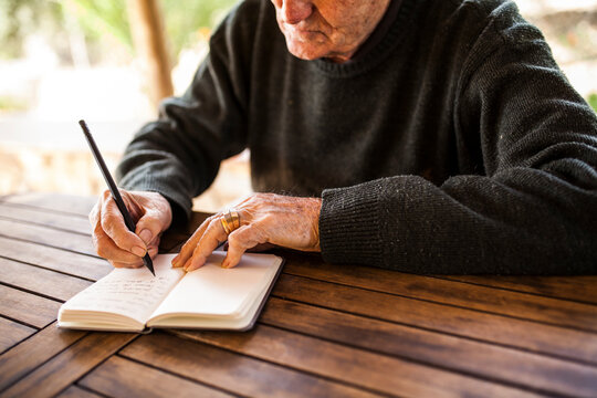 elderly man writing in his notebook