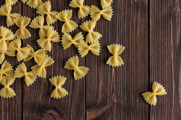 Raw pasta farfalle with copy space on wooden background.