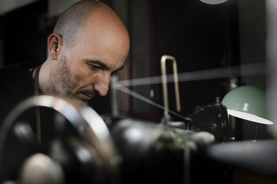Man stitching textile in atelier