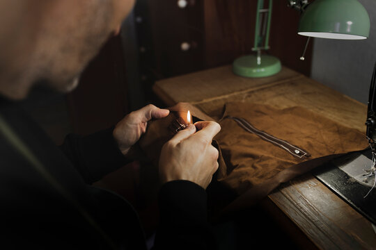 Man searing edges of textile in darkness