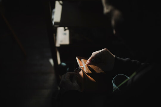 Anonymous man sewing textile in atelier