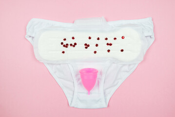 panties, pads, menstrual cup on a pink background.