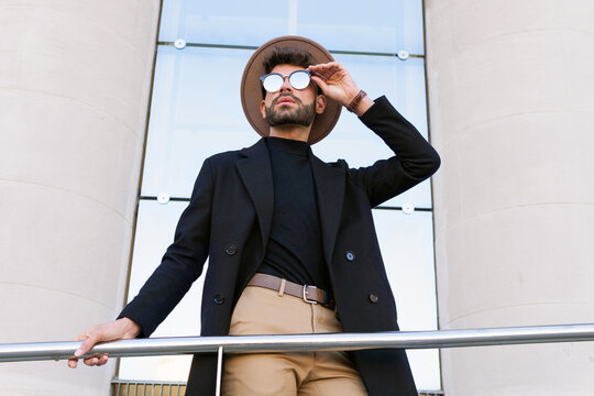 Masculine man in trendy sunglasses behind handrail in town