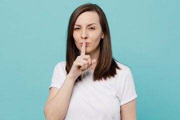 Young secret caucasian woman 20s she wear white t-shirt say hush be quiet with finger on lips shhh gesture isolated on plain pastel light blue cyan background studio portrait People lifestyle concept