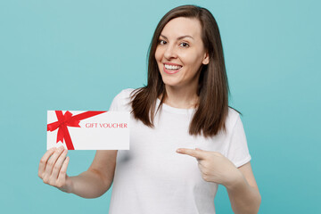Young happy funwoman 20s she wear white t-shirt hold point index finger on gift certificate coupon voucher card for store isolated on plain pastel light blue cyan background People lifestyle concept