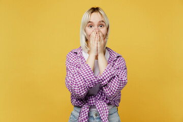 Young shocked surprised amazed blonde woman 20s she wear pink tied shirt white t-shirt look camera cover mouth with hands isolated on plain yellow background studio portrait. People lifestyle concept.