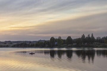 Sunset over the lake. Calm rural picture. The fisherman returns home.