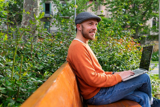 Cheerful man browsing laptop in park