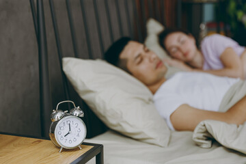 Young calm couple two family man woman she he wear t-shirt pajama lying in bed sleeping rest spend...