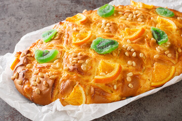 Traditional Spanish Catalan coca de Sant Joan with pine nuts, candied fruit closeup on the paper on the table. Horizontal