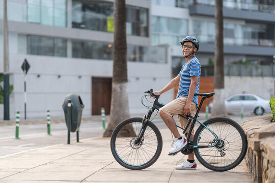 Happy latin man riding bicycle on sidewalk